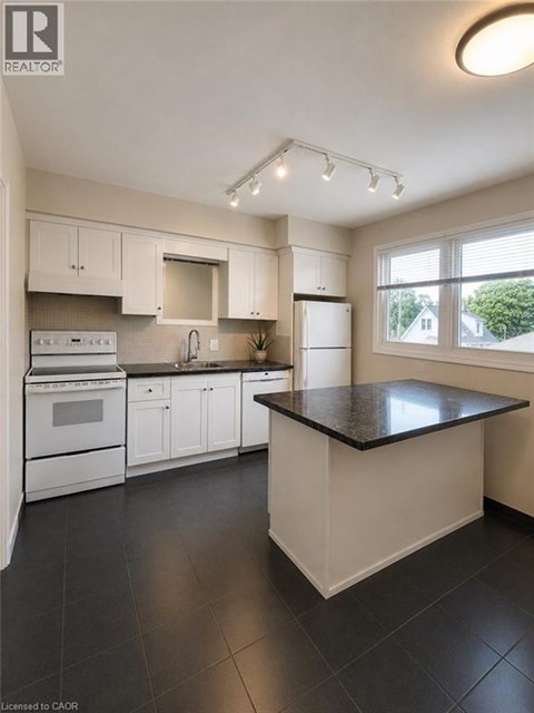 A kitchen with black countertops and white appliances.