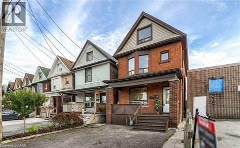 A house with a brown roof and a sign that says "REALTOR" in front of it.