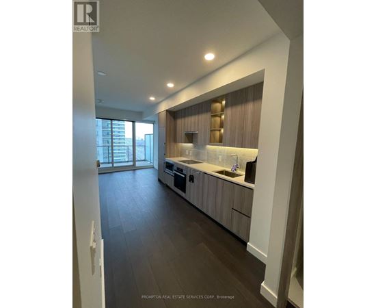 A modern kitchen with dark wood floors and white walls.