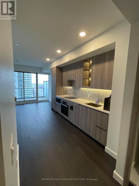 A modern kitchen with dark wood floors and white walls.