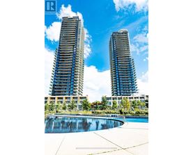 Two tall buildings with balconies are surrounded by a pool.