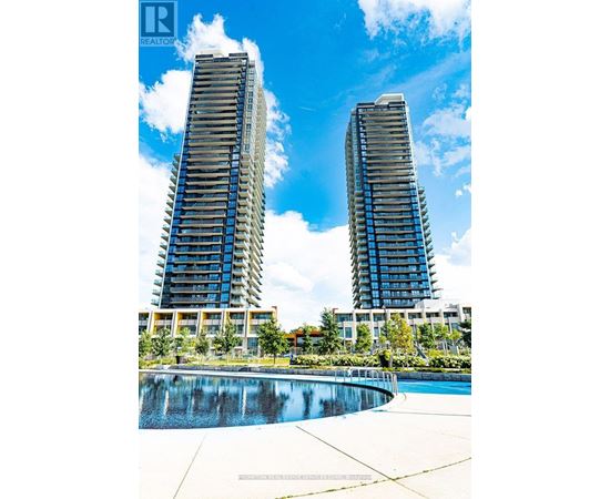 Two tall buildings with balconies are surrounded by a pool.