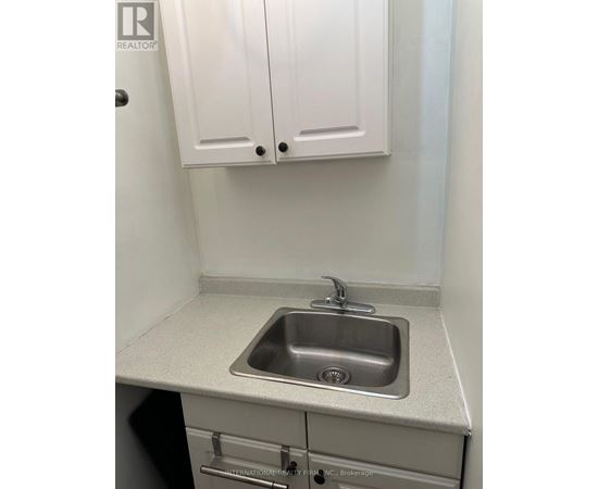 A small white kitchen with a sink and cabinets.