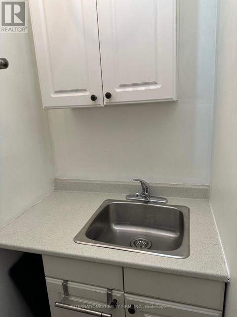 A small white kitchen with a sink and cabinets.