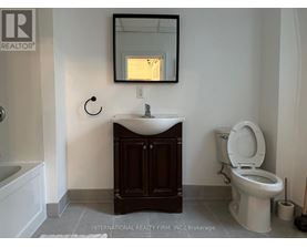 A bathroom with a toilet, sink, and mirror.