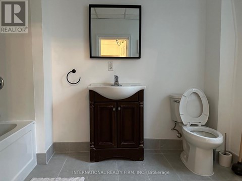 A bathroom with a toilet, sink, and mirror.