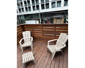 Two chairs and a small table are on a wooden deck.