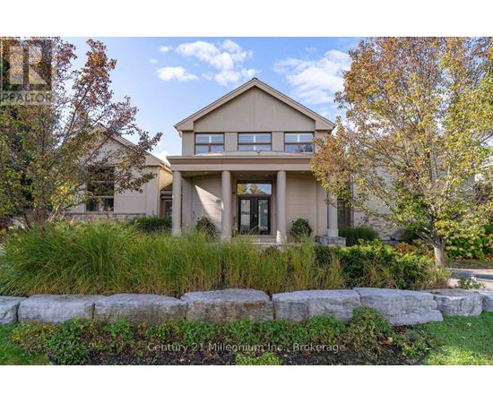 A beige house with a stone wall in front.