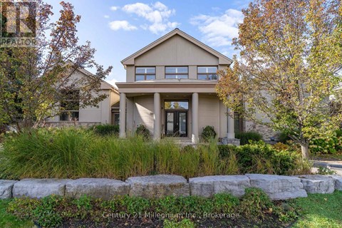 A beige house with a stone wall in front.