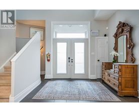 A hallway with a staircase on the left and a wooden dresser on the right.