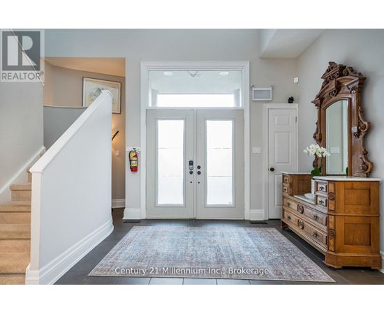 A hallway with a staircase on the left and a wooden dresser on the right.