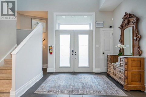 A hallway with a staircase on the left and a wooden dresser on the right.