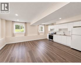A well-lit, spacious kitchen with white cabinets and a wooden floor.