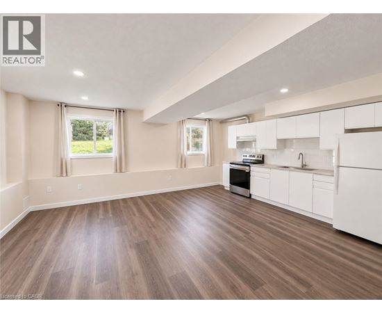 A well-lit, spacious kitchen with white cabinets and a wooden floor.
