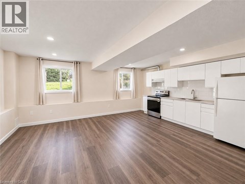 A well-lit, spacious kitchen with white cabinets and a wooden floor.