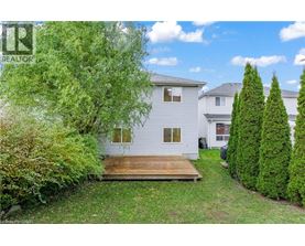 A white house with a wooden deck in the front yard.