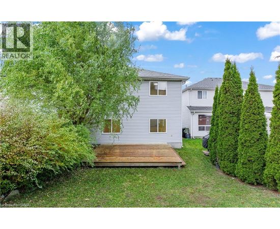 A white house with a wooden deck in the front yard.