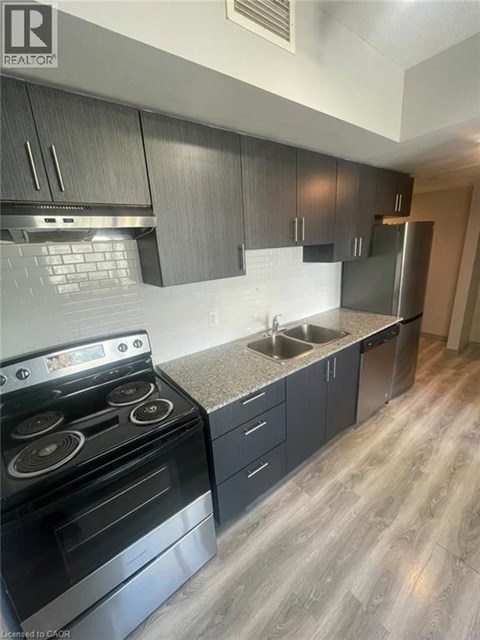 A modern kitchen with a stove, sink, and cabinets.