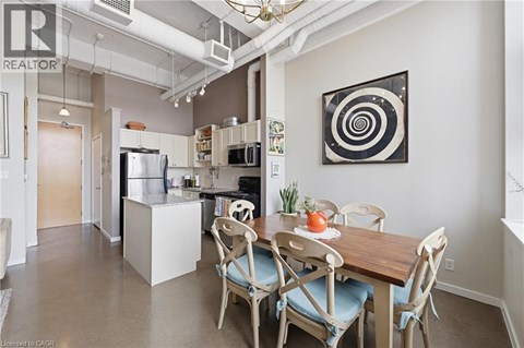 A dining room with a table set for two and a fridge in the corner.