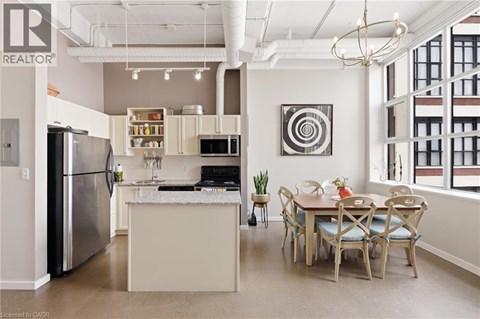 A kitchen with a refrigerator, a table and chairs, and a dining area.