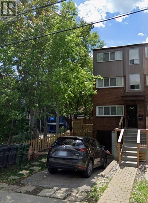 A black car is parked in front of a brown building.