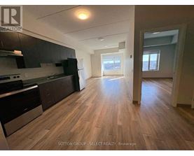A kitchen with dark wood floors and a stainless steel refrigerator.