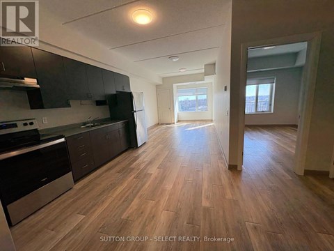 A kitchen with dark wood floors and a stainless steel refrigerator.