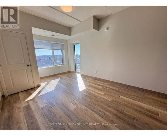 A room with wooden flooring and a large window overlooking a cityscape.