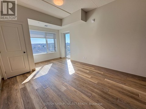 A room with wooden flooring and a large window overlooking a cityscape.