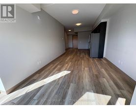 A room with wooden flooring and a refrigerator in the corner.