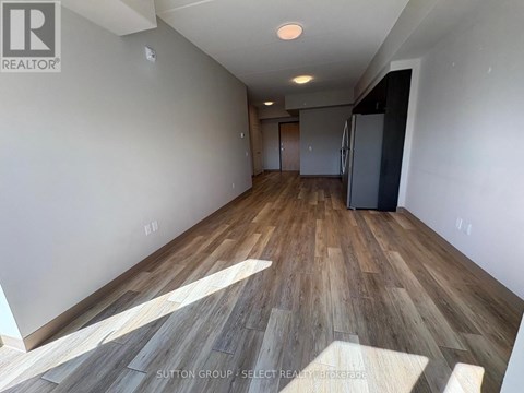 A room with wooden flooring and a refrigerator in the corner.