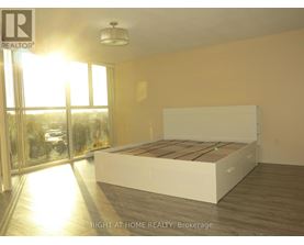 A bedroom with a large bed and a view of the outside through a glass door.