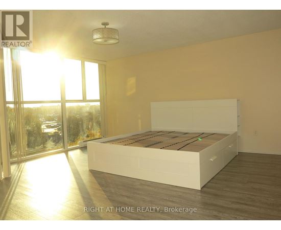 A bedroom with a large bed and a view of the outside through a glass door.