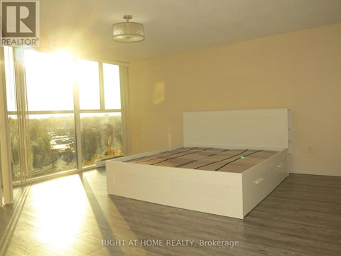 A bedroom with a large bed and a view of the outside through a glass door.