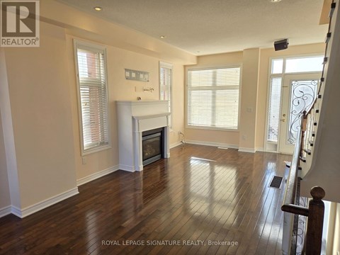 A spacious living room with wood flooring and a fireplace.