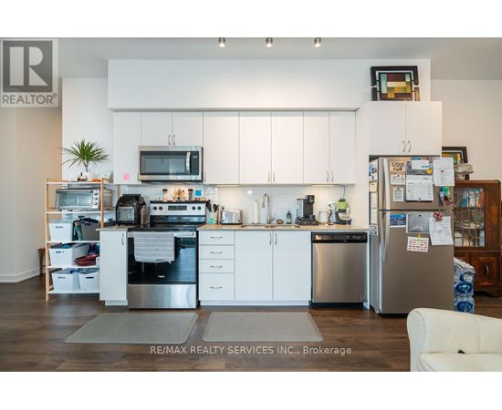 A kitchen with white cabinets and a refrigerator with a lot of papers attached to it.