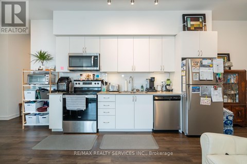 A kitchen with white cabinets and a refrigerator with a lot of papers attached to it.