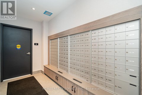 A black door with a yellow sign on it and a wall of mailboxes.