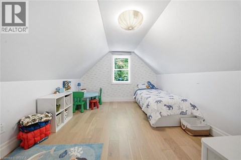 A bedroom with a bed, a chair, a table, and a window.