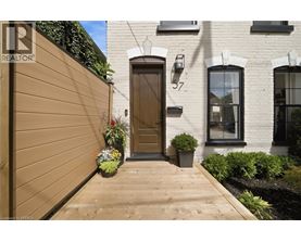 A brown wooden door is on the left side of a white building with a black window.