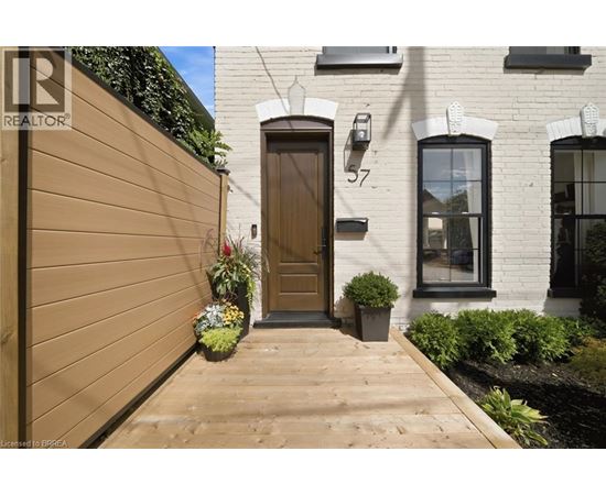 A brown wooden door is on the left side of a white building with a black window.