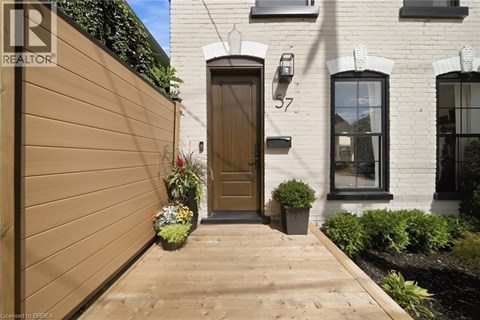 A brown wooden door is on the left side of a white building with a black window.