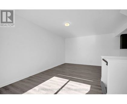A room with a white wall and a wooden floor with a rug on it.