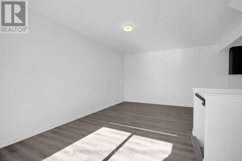 A room with a white wall and a wooden floor with a rug on it.