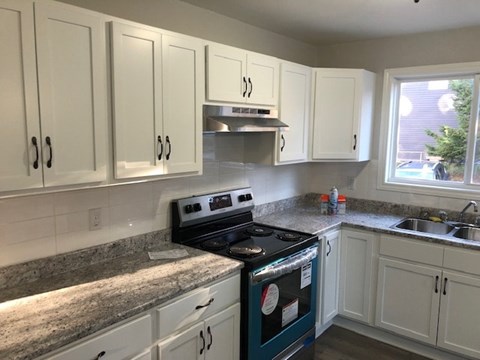 A kitchen with a blue stove top oven and white cabinets.