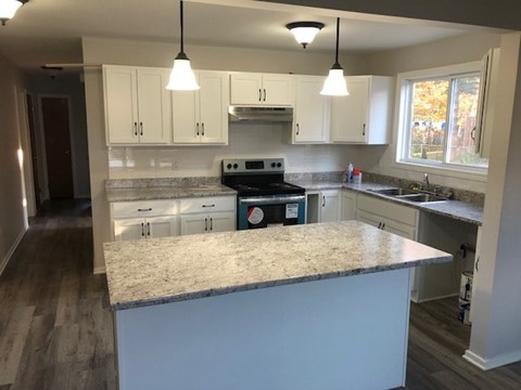 A kitchen with a granite countertop and white cabinets.