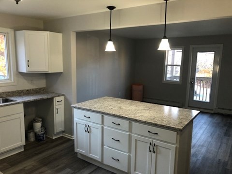 A kitchen with white cabinets and a granite countertop.