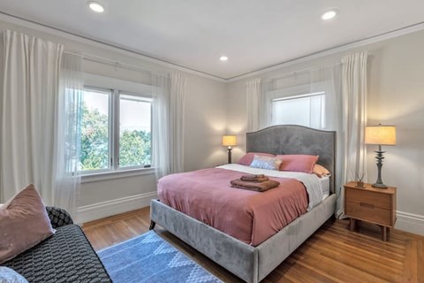 A bedroom with a large bed and a window with curtains.