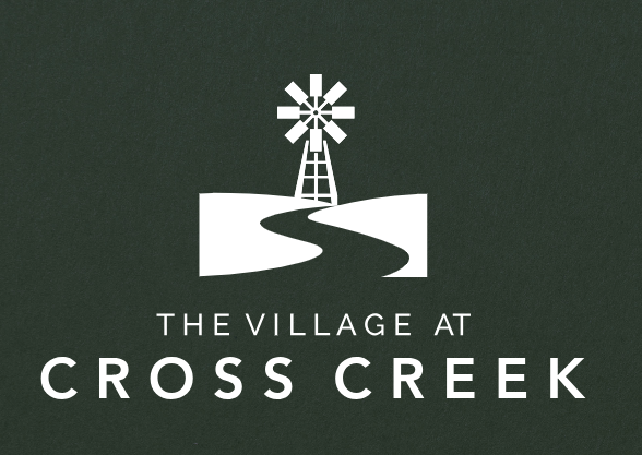 A logo with a windmill on a green background that says "The Village at Cross Creek".