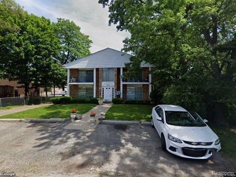 A white car is parked in front of a house.